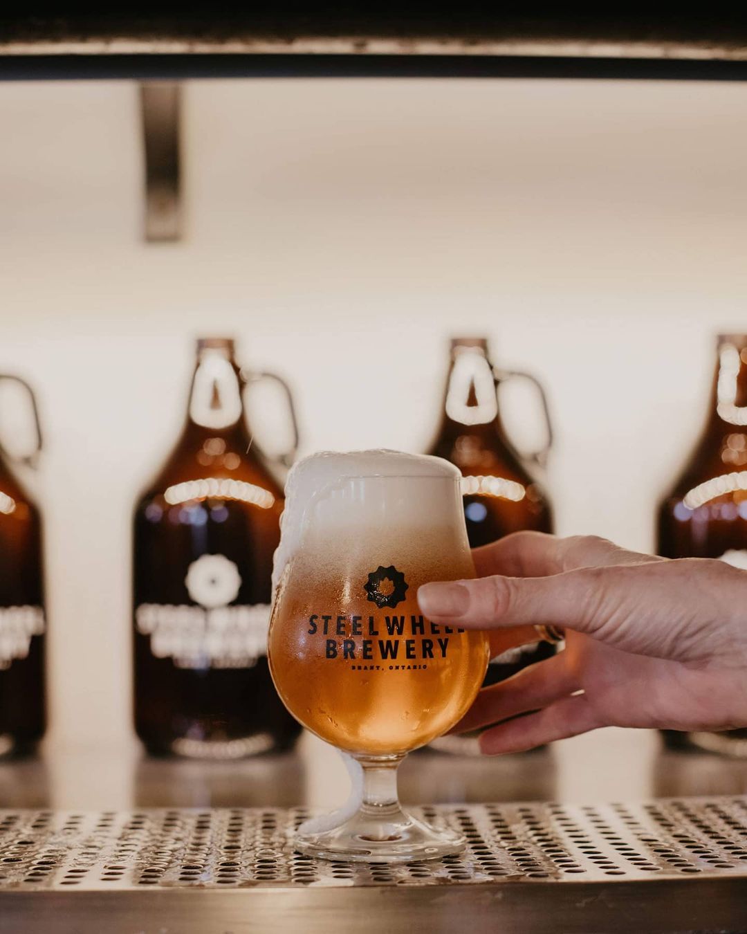 A person holding up beer at Steel Wheel Brewery